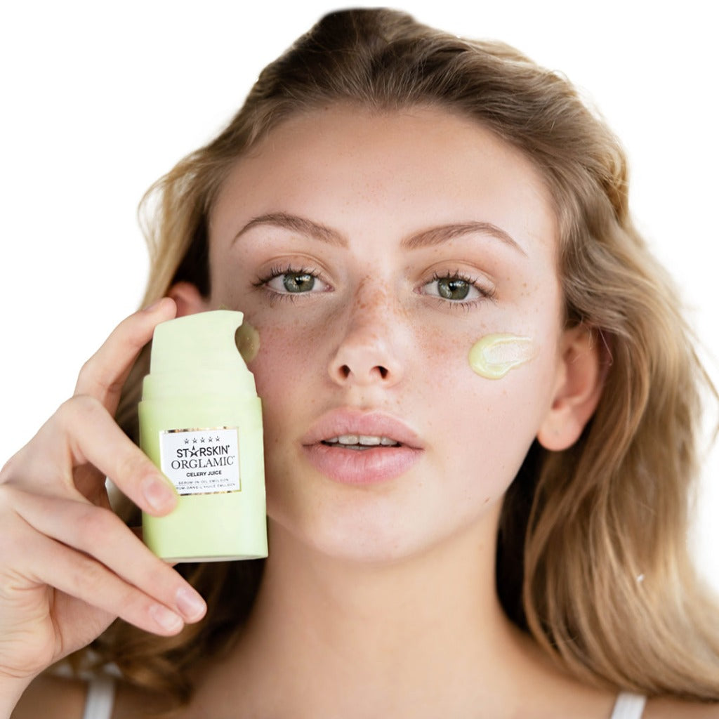 Atmospheric image of a model holding the STARSKIN ORGLAMIC Celery Juice Serum-In-Oil Emulsion in her hand. On her face two swipes of the green substance from the STARSKIN ORGLAMIC Celery Juice Serum-In-Oil Emulsion