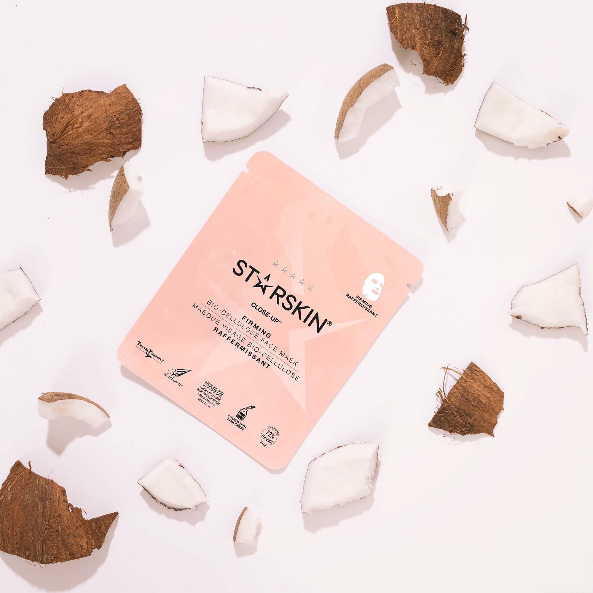Inside packaging of the close up face sheet mask, surrounded by broken coconut pieces