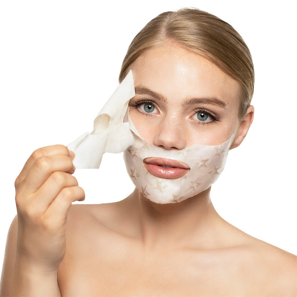 Model wearing the STARSKIN VIP Cream de la Crème Age perfecting face mask and removing the top part from her face