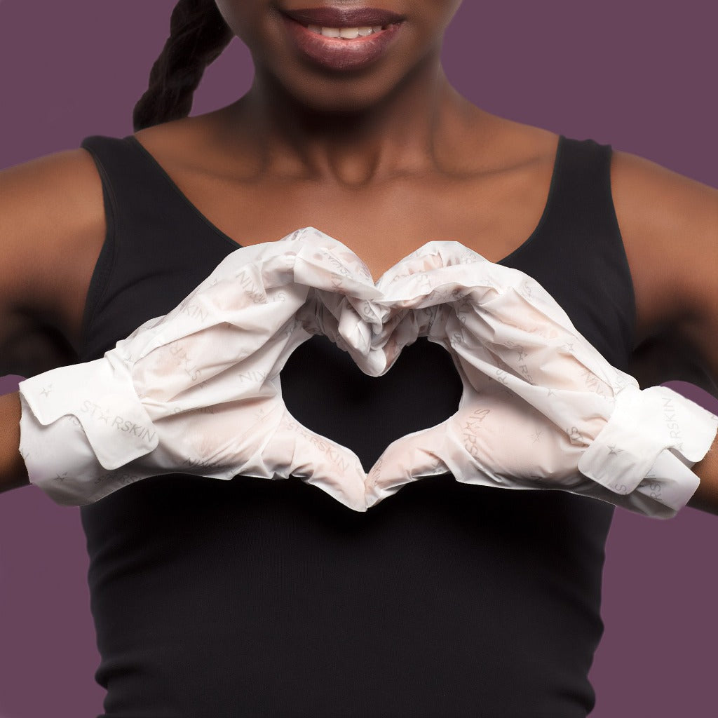 Atmospheric image where a model wears the STARSKIN Hollywood Hand mask and makes a heart with her hands